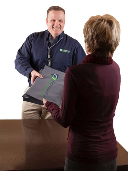 A CI Information Management employee handing a CI-branded package to another person.