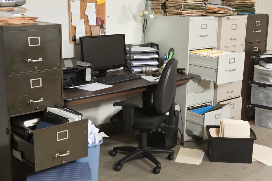 A very messy office with files spilling out of open file cabinets