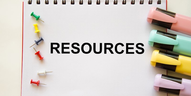 "Resources" is written in black block text on a white notepad with multicolored highlighters arranged at its side