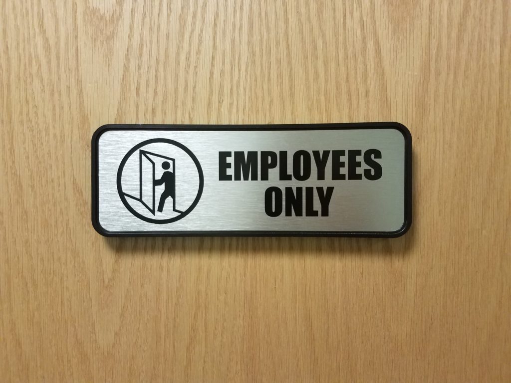 silver and black employees only sign on wood door