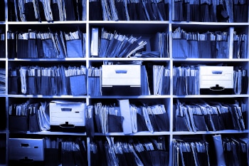 A bookshelf full of files. The image has a blue filter over it.