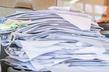 A messy stack of office documents and papers on a table.